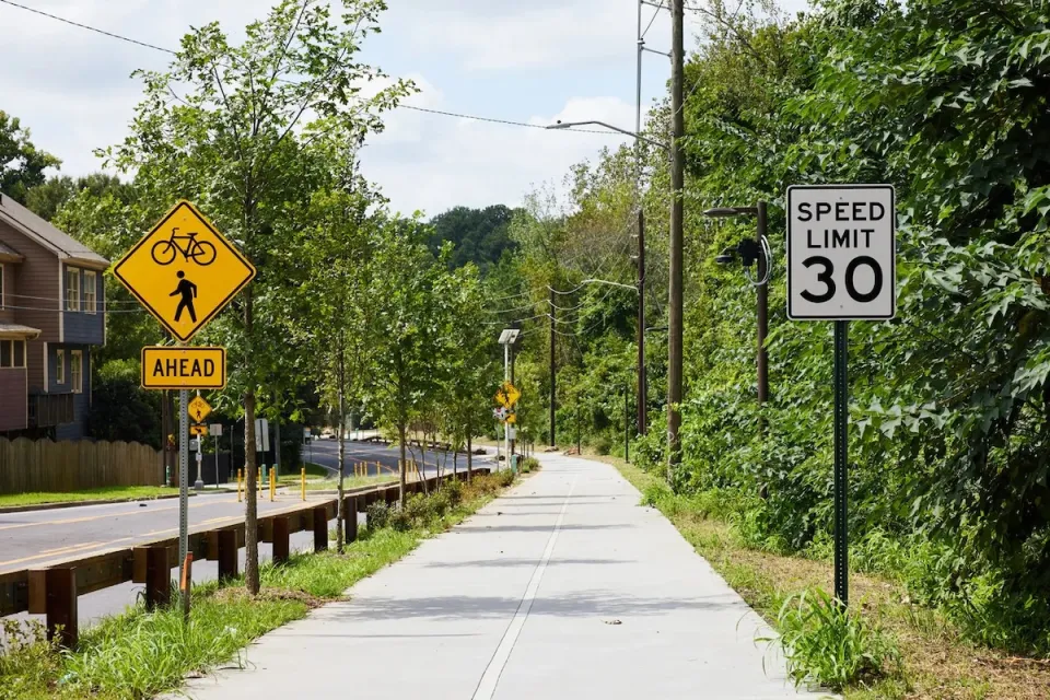 Paved Atlanta Beltline trail segment next to street with bike and pedestrian crossing sign and 30 mph speed limit sign.